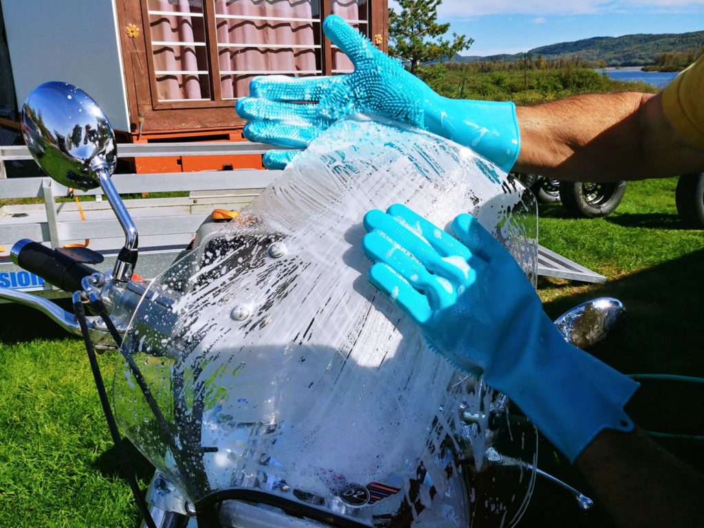Silicone gloves washing windshield of motor bike.